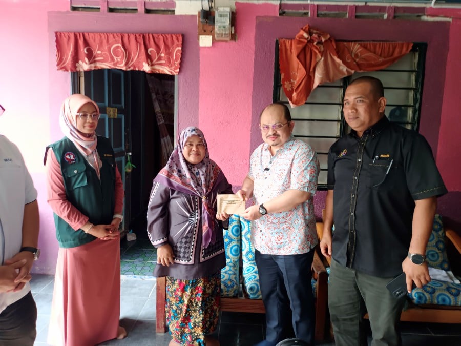 ALOR GAJAH -- The Prime Minister’s senior political secretary, Datuk Seri Shamsul Iskandar Mohd Akin (Second from right) hands over RM500 emergency assistance contribution from Prime Minister Datuk Seri Anwar Ibrahim to local resident Idah Borhan, 48 (Second from left), who was one of thirteen residents of Durian Tunggal whose houses were flooded last week. — BERNAMA