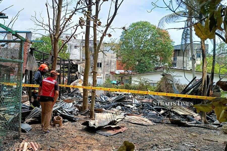 A total of 12 people, from two families, fled in time from a fire which gutted two semi-detached wooden houses in Lorong Zakaria in Alor Gajah town, here, this morning. - NSTPO/MEOR RIDUWAN MEOR AHMAD