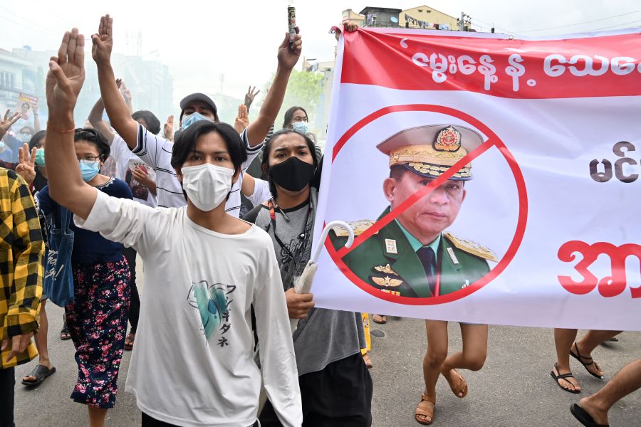Protesters make the three-finger salute beside a banner featuring Myanmar armed forces chief Senior General Min Aung Hlaing as they take part in a demonstration against the military coup in Yangon on July 3. - AFP PIC
