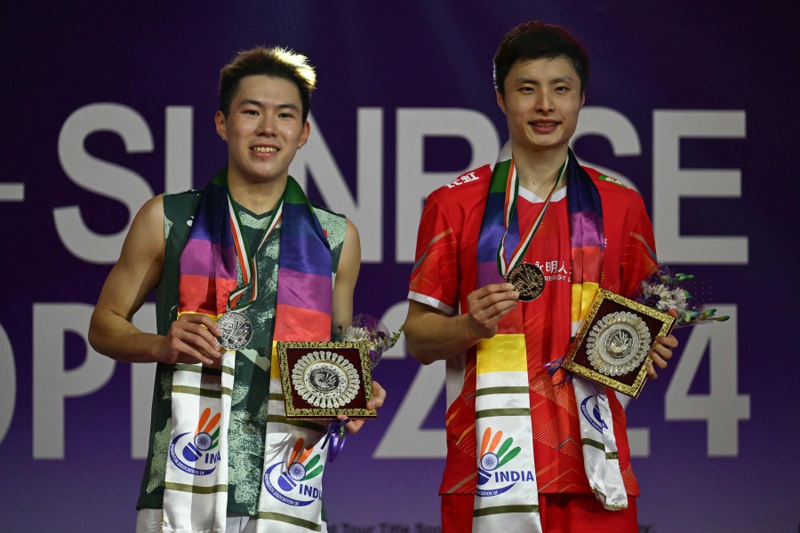 China's Shi Yuqi(R) poses with the trophy after winning against Hong Kong's Lee Cheuk Yiu during men final at India Open badminton tournament held at Indira Gandhi Stadium on January 21, 2024. AFP PIC