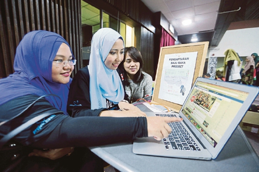 Aida (centre) and colleagues checking out some information on Facebook. Pix by MOHD KHAIRUL HELMY MOHD DIN.
