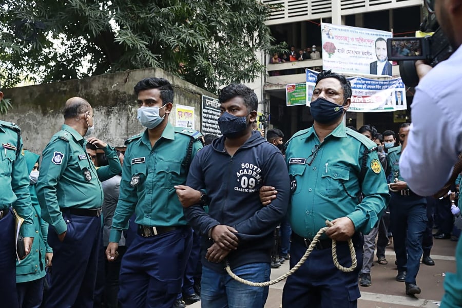 Police escort one of the 20 convicted university students, after their sentence to death for the brutal 2019 murder of a young man who criticised the government on social media, out of a court in Dhaka on December 8, 2021. (Photo by AFP)