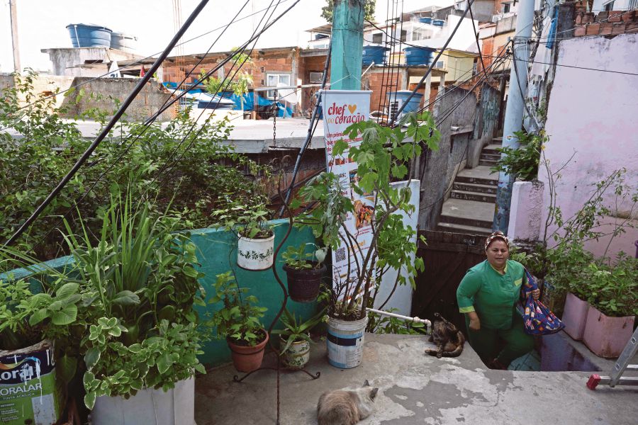 Regina Tchelly, founder of the Favela Organica initiative, enters a house at the Babilonia favela in Rio de Janeiro, Brazil. (Photo by Pablo PORCIUNCULA / AFP)