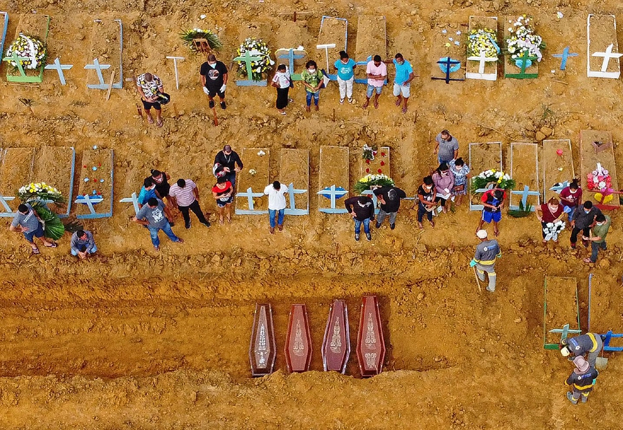 (FILES) This file aerial picture taken on April 22, 2020 shows a burial taking place at an area where new graves have been dug up at the Nossa Senhora Aparecida cemetery in Manaus, in the Amazon forest in Brazil, during the COVID-19 coronavirus pandemic. - Brazil's COVID-19 death toll passed 15,000 on May 16, 2020, official figures showed, while its number of infections topped 230,000, making it the country with the fifth highest number of cases in the world. (Photo by Michael DANTAS / AFP)