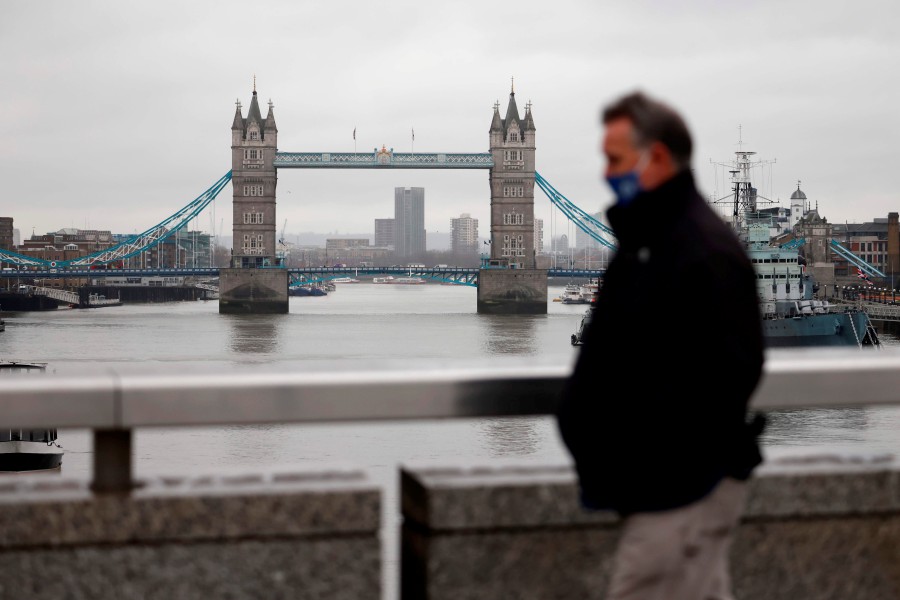 Pedestrians walk over London bridge as Britain enters a national lockdown in London on January 5, 2021. - England's six-week lockdown, which began at midnight, emulates the first national coronavirus curbs in place from March to June -- but goes further than another instituted in November when schools remained open. Authorities in Wales, Scotland and Northern Ireland have all taken similar measures, putting the UK as a whole in lockdown. (Photo by Tolga Akmen / AFP)