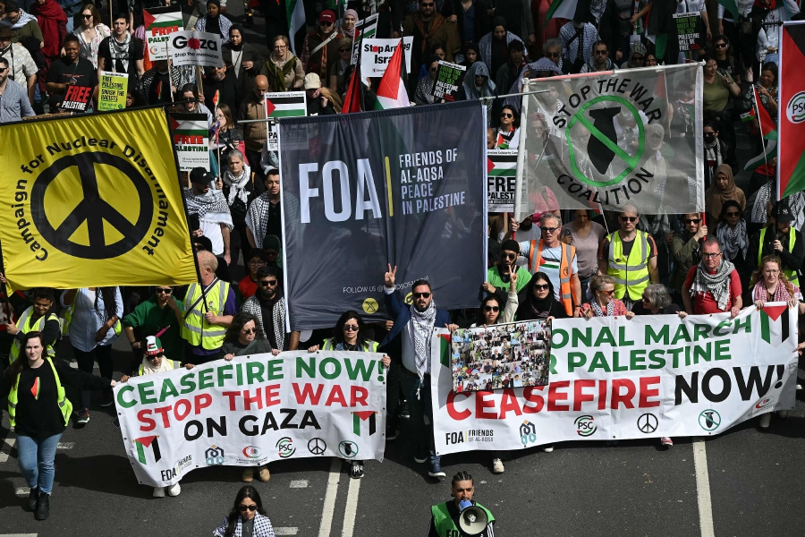 Pro-Palestinian activists and supporters wave flags and hold placards as during a protest march in central London, during a National Day of Action calling for a ceasefire in the Israel-Hamas war. (Photo by JUSTIN TALLIS / AFP)