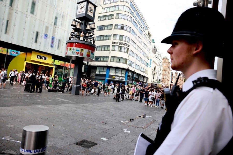 A police officer stands guard by a cordoned off area in Leicester square, London. A woman and an 11-year-old girl were hospitalised on Monday (Aug 12) after being stabbed in central London's famous Leicester Square. — AFP