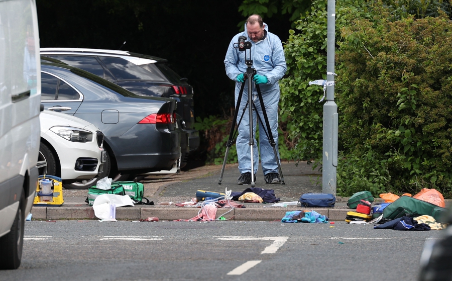 Police forensic officers examine the crime scene in Hainault, east of London. (Photo by Adrian DENNIS / AFP)