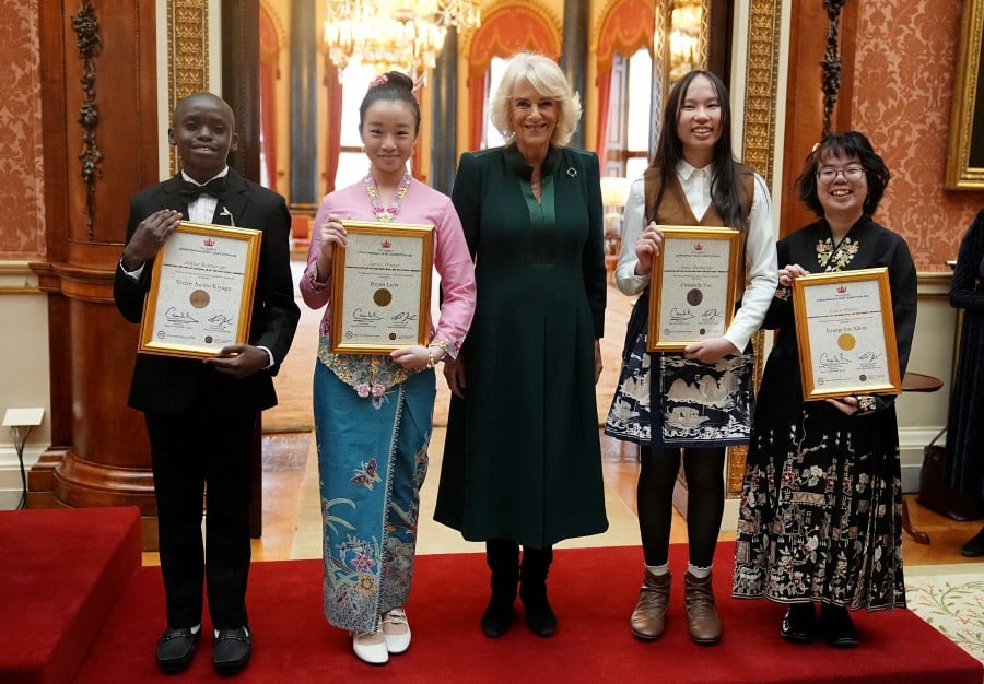 Queen Camilla stands with, Junior Winner Erynn Liew (Second from left) and Senior Winner Evangeline Khoo (Right) during a reception for winners of the Queen's Commonwealth Essay Competition, at Buckingham Palace in London, yesterday (Nov 21). — REUTERS PIC