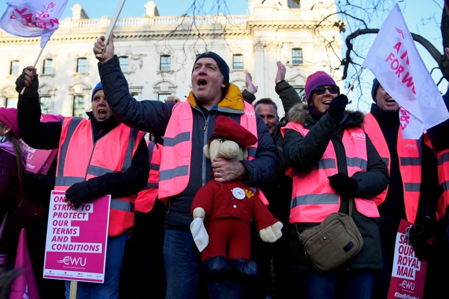 A Royal Mail worker holds a toy depicting Postman Pat as members strike over pay and conditions, outside of the Houses of Parliament in London, Britain. -REUTERS file pic