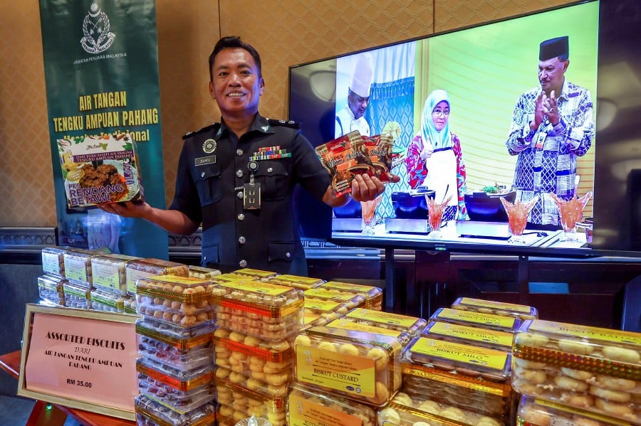 Bentong Prison Superintendent Mohd Zulkifli Zakaria holding up a box of ‘rendang betawi’ and ‘asam pedas’ paste at a stall which also features Raya cookies made by prison inmates using Tengku Ampuan Pahang Tunku Azizah Aminah Maimunah Iskandariah’s recipes during a Prisons Department’s event at the Banquet Hall of the Palace of Justice in Putrajaya, recently. - Bernama pic