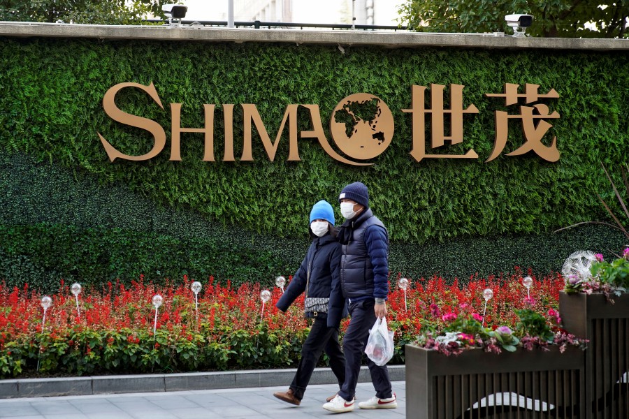FILE PHOTO: People walk past the logo of property developer Shimao Group near Shimao Tower in Shanghai, China January 13, 2022. REUTERS/Aly Song/File Photo