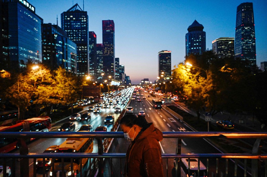 A woman walks on an overpass at the central business district in Beijing on November 14, 2023. (Photo by Jade Gao / AFP)