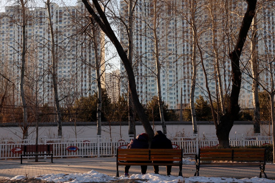 People sit on a bench at a park near residential buildings in China. REUTERS/Florence Lo/File Photo