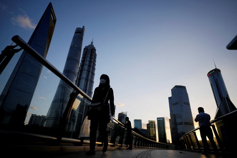 FILE PHOTO: People walk on an overpass past office towers in the Lujiazui financial district of Shanghai, China. REUTERS/Aly Song/File Photo