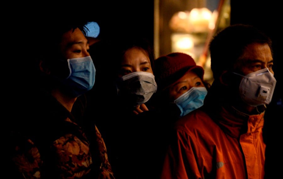 People wearing protective face masks queue to order food from a stall in Shanghai. - AFP pic