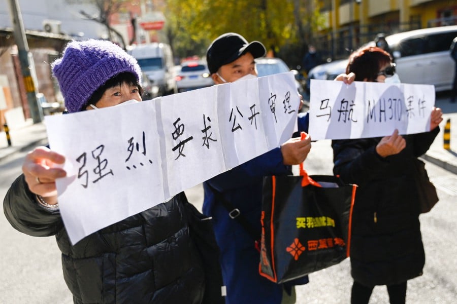 Relatives of passengers of the missing Malaysia Airlines flight MH370 hold a sign reading "We Strongly demand a public trial of the Malaysia Airlines MH370 cases" close to a court building in Beijing on November 27, 2023. AFP PIC