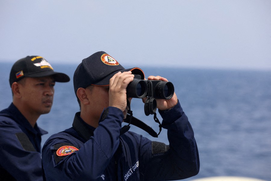 A Philippine Coast Guard personnel looks through a binocular while conducting a resupply mission for Filipino troops stationed at a grounded warship in the South China Sea. - (REUTERS pic)