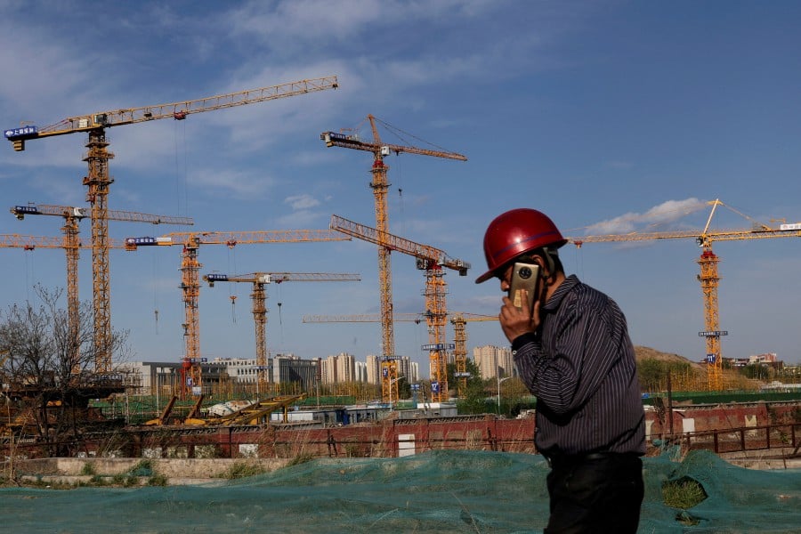 FILE PHOTO: FILE PHOTO: A worker speaking on his phone walks past a construction site in Beijing, China April 14, 2022. Picture taken April 14, 2022. REUTERS/Tingshu Wang/File Photo/File Photo