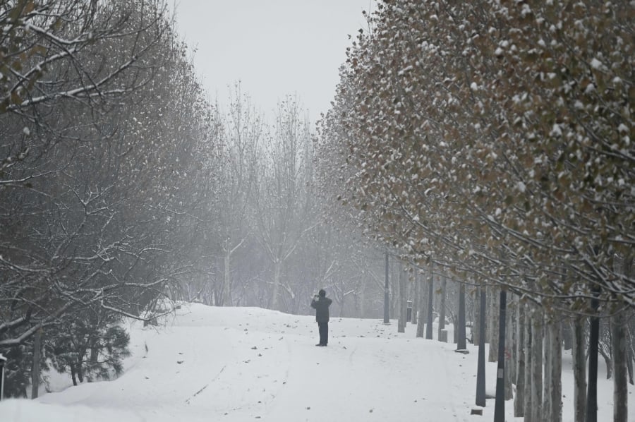 A man takes photos on a snowy day in Beijing. (Photo by WANG Zhao / AFP)