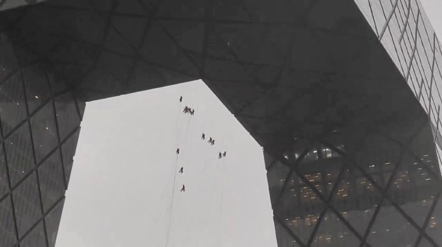 Workers hang from a building amid strong winds in Beijing, China in this screen grab obtained from a social media video. (Video obtained by Reuters/via REUTERS)