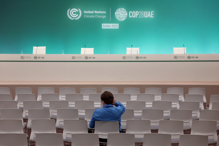 A person waits for a press conference to start before it was declared canceled, while negotiations continue during the final stages of the United Nations Climate Change Conference COP28, in Dubai, United Arab Emirates. (REUTERS/Amr Alfiky)