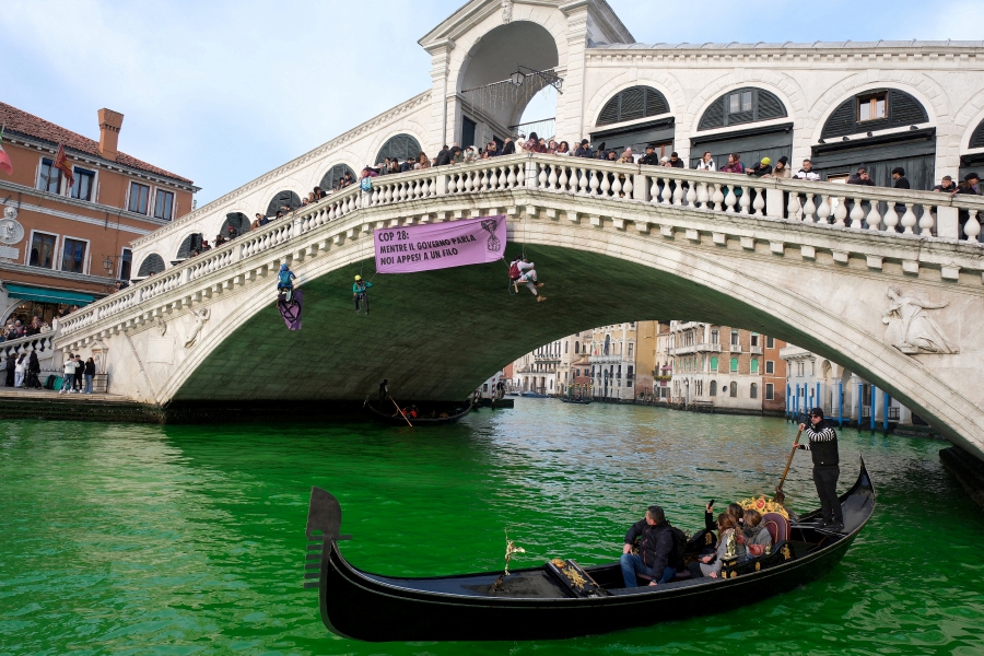 People ride in boats as waters of Grand Canal turned green after a protest by 'Extinction Rebellion' climate activists in Venice, Italy. - REUTERS/Manuel Silvestri