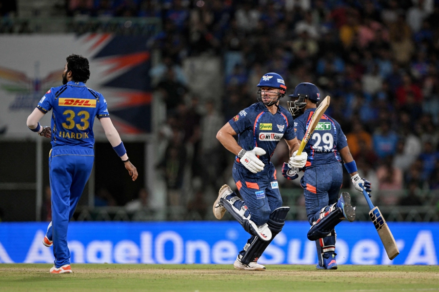 Lucknow Super Giants' Marcus Stoinis (centre) runs between the wickets as Mumbai Indians' captain Hardik Pandya (left) looks on during the Indian Premier League (IPL) Twenty20 cricket match between Lucknow Super Giants and Mumbai Indians at the Ekana Cricket Stadium in Lucknow. (Photo by Arun SANKAR / AFP) / -- 