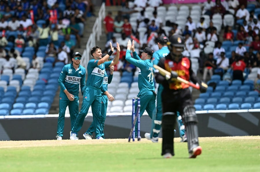 New Zealand's players congratulates New Zealand's Trent Boult (centre) after dismissing Papua New Guinea's Hiri Hiri during the ICC men's Twenty20 World Cup 2024 group C cricket match between New Zealand and Papua New Guinea at Brian Lara Cricket Academy Stadium in Tarouba, Trinidad and Tobago. (Photo by Marco BELLO / AFP)