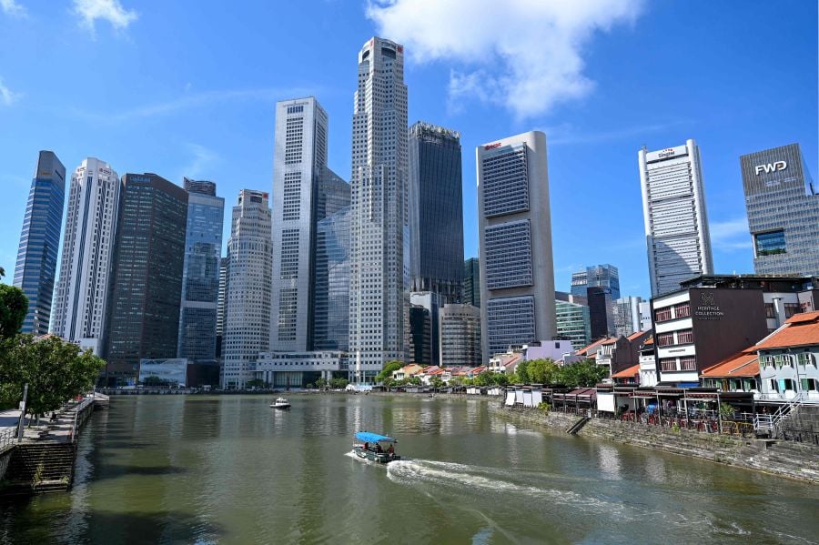 A boat cruises on the water in the central financial business district area in Singapore. - Singapore today joined Malaysia in ruling out hosting the 2026 Commonwealth Games, further plunging the future of the multi-sport event into doubt. - AFP pic