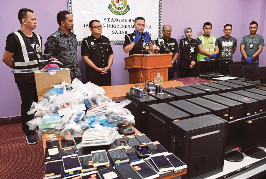 Sabah Immigration Department director Datuk Muhamad Sade Mohamad Amin (four, left) with a plunder while holding a press conference on the success of the Sabah Immigration Department overcame a Chinese-based online investment fraud syndicate operating a fraudulent activity here.--BERNAMA