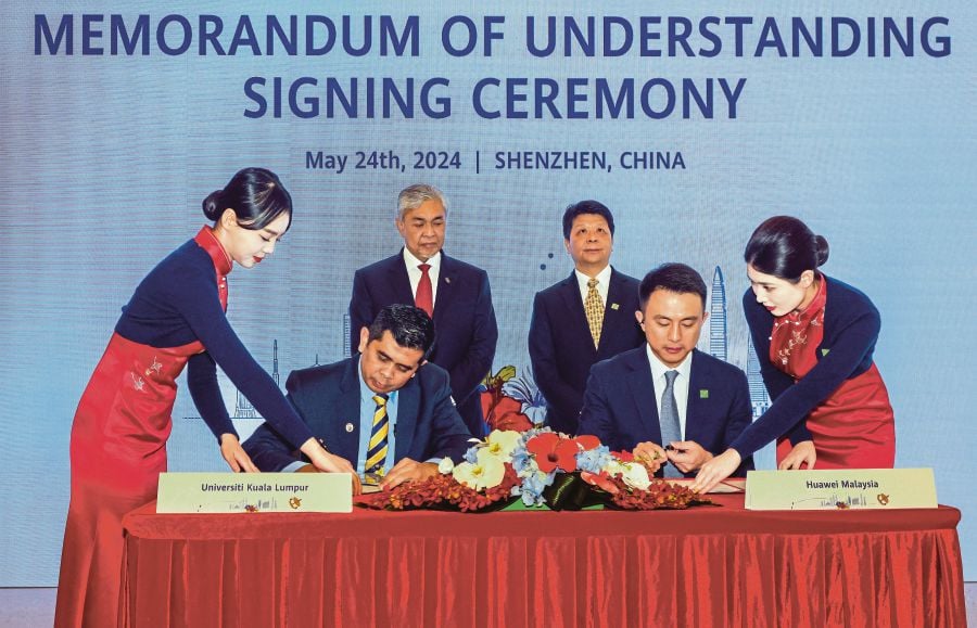 Deputy Prime Minister Datuk Seri Dr Ahmad Zahid Hamidi (standing, left) witnessing the signing of MoU between chief executive officer of UniKL, Prof Madya Ir Dr Azman Senin (seated, left) and chief executive officer of Huawei Malaysia Simon Sun (seated, right). - BERNAMA pic