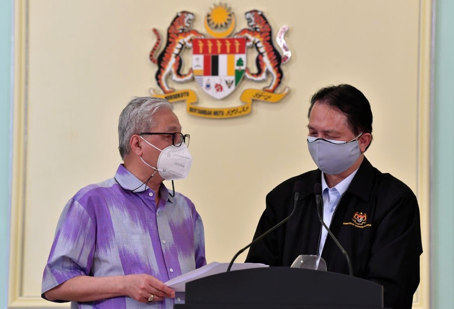 Senior Minister (Security Cluster) Datuk Seri Ismail Sabri Yaakob (left) having a discussion with Health Director-General Tan Sri Dr. Noor Hisham Abdullah (right) before a press conference regarding a full Movement Control Order (MCO) for the economic and social sectors at the Perdana Putra building today. -Bernama pic