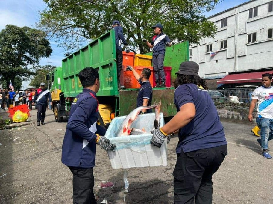 DBKL enforcement officers carrying various seized goods belonging to foreign vendors operating in public spaces in the northern city centre, particularly around the Selayang wholesale market and Taman Batu View.- pic credit FB/DBKL
