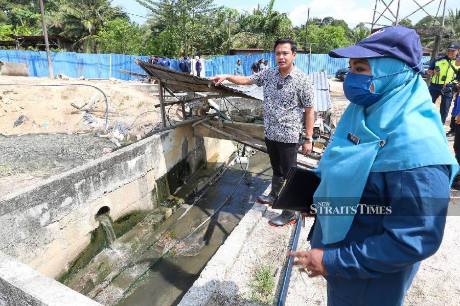 Penang Agrotechnology, Food Security and Cooperative Development Committee chairman Fahmi Zainol (second from right) and Penang Veterinary Services Department director Dr Saira Banu Mohamed Rejab (right) inspecting the site where farm waste was reported to have been discharged into Sungai Kulim.- NSTP/DANIAL SAAD 