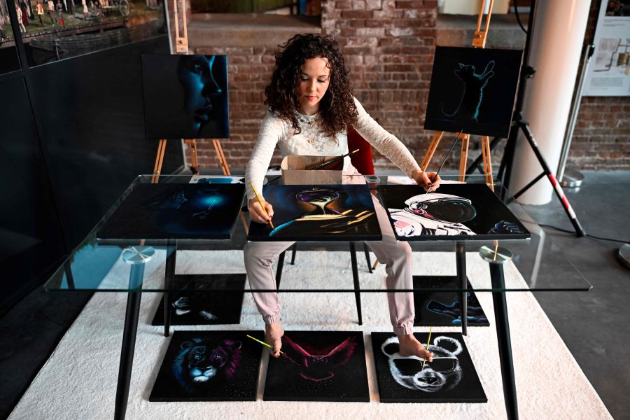 Dutch artist Rajacenna van Dam, paints ten paintings at once with both hands and feet, live in a museum in Vlaardingen. - AFP pic