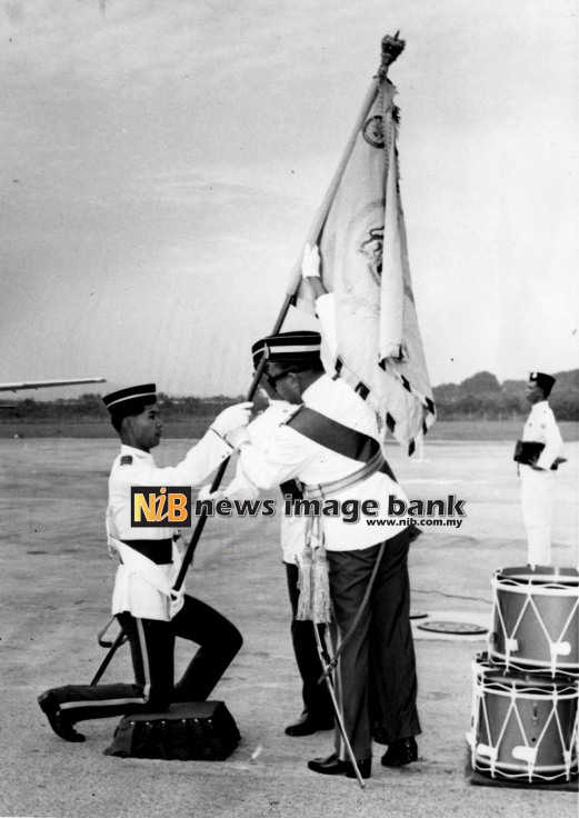 14 March 1967: The Yang di-Pertuan Agong presented His Majesty's Colours to the Royal Malaysian Air Force at the RMAF base in Kuala Lumpur. Picture shows Colour Bearer, Flight Lieutenant Buang bin Ahmad, receiving the Colours from His Majesty (right).
