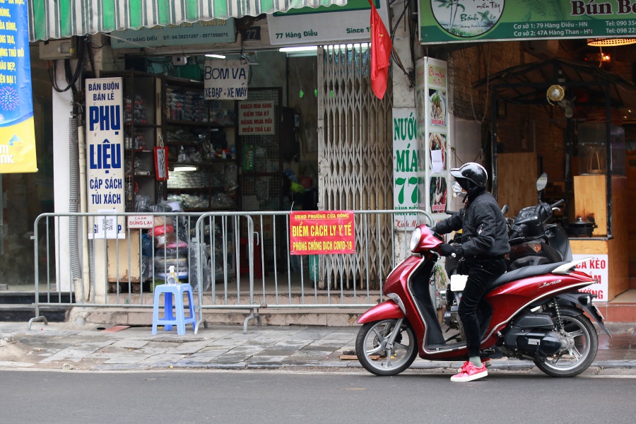 A woman rides motorbike past a 'quarantine area' at a street in Hanoi, Vietnam. - EPA Pic