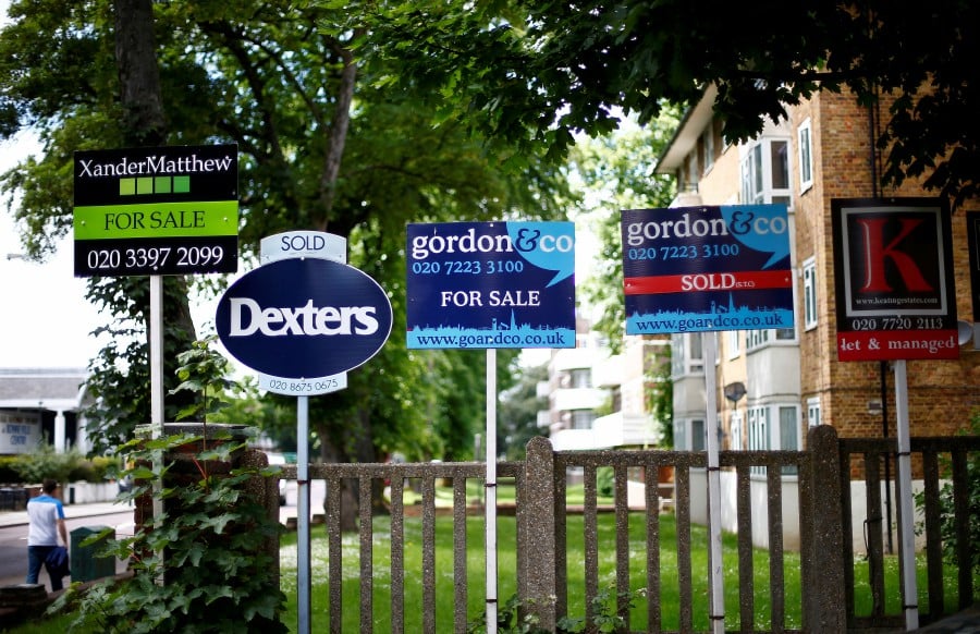 FILE PHOTO: Estate agents boards are lined up outside houses in south London June 3, 2014. REUTERS/Andrew Winning/File Photo