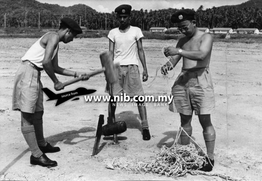 21 August 1953: A three man detail on fatigue duty, erecting clothes lines at the grounds of the Malayan Air Training Corps.