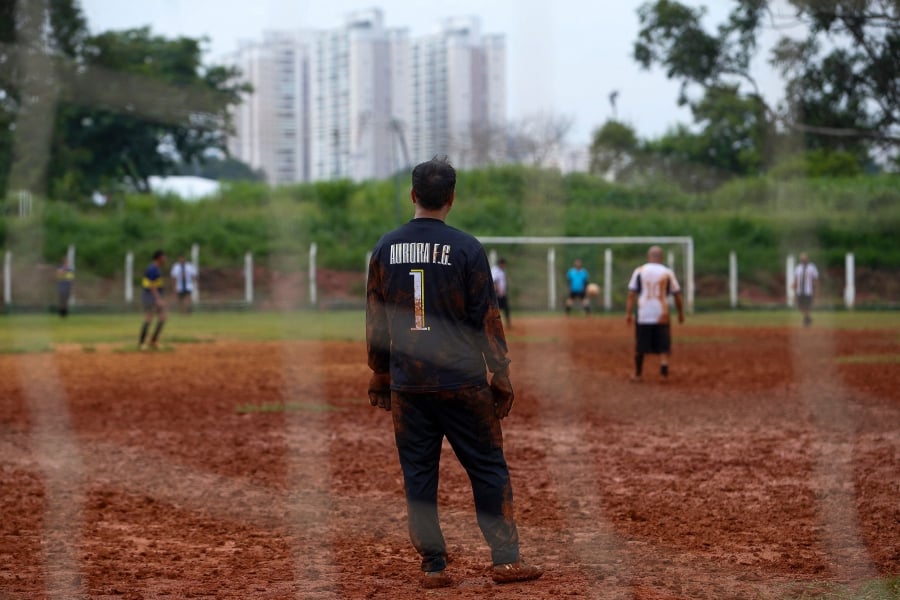 Locals play football in a dirt field in Sao Paulo, Brazil. (Photo by Miguel SCHINCARIOL / AFP)