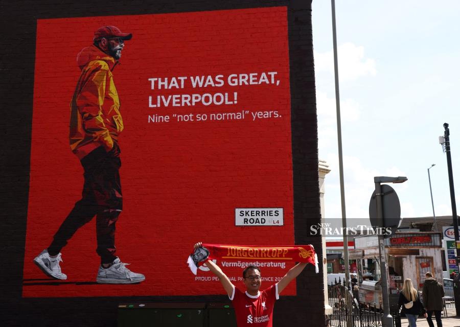 A Liverpool fan poses with in front of a street artwork depicting Liverpool manager Jurgen Klopp ahead of the Premier League football match between Liverpool and Tottenham Hotspur, near Anfield on Sunday. AFP PIC
