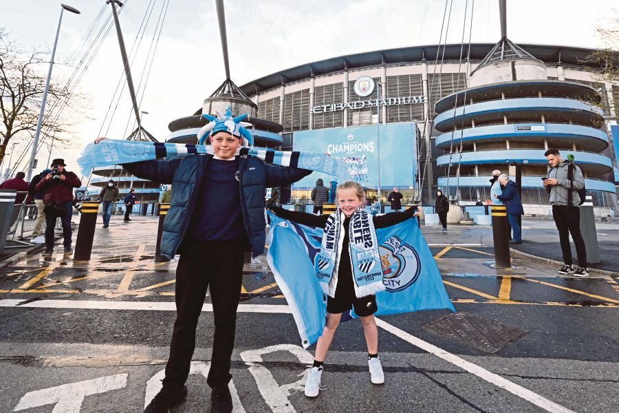 Young Manchester City fan celebrate their club winning the Premier League title, outside the Etihad Stadium in Manchester, north west England, on May 11, 2021, after their closest challengers for the title Manchester United, lost to Leicester City this evening. - (Photo by Paul ELLIS / AFP)