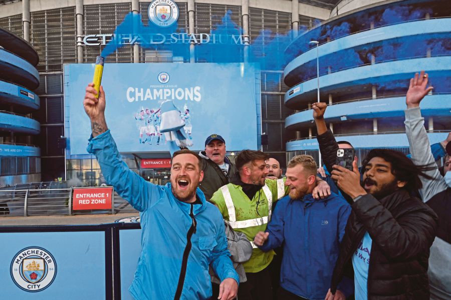 Manchester City fans celebrate their club winning the Premier League title, outside the Etihad Stadium in Manchester, north west England, on May 11, 2021, after their closest challengers for the title Manchester United, lost to Leicester City this evening. - (Photo by Paul ELLIS / AFP)