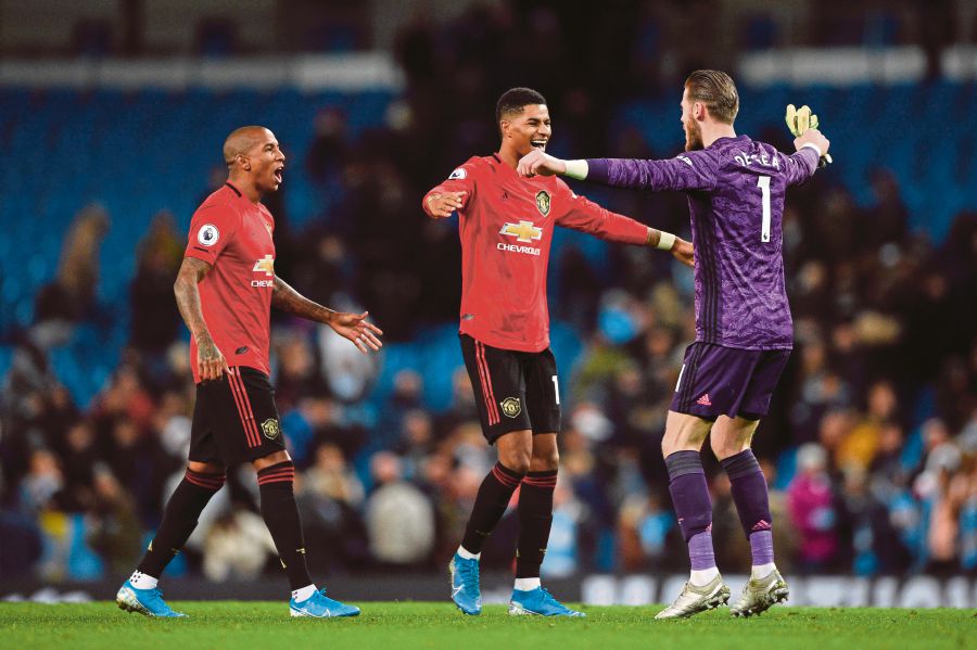(L-R) Manchester United's English defender Ashley Young, Manchester United's Spanish goalkeeper David de Gea and Manchester United's English striker Marcus Rashford celebrate victory at the end of the English Premier League football match between Manchester City and Manchester United at the Etihad Stadium in Manchester, north west England, on December 7, 2019. (Photo by Oli SCARFF / AFP) 