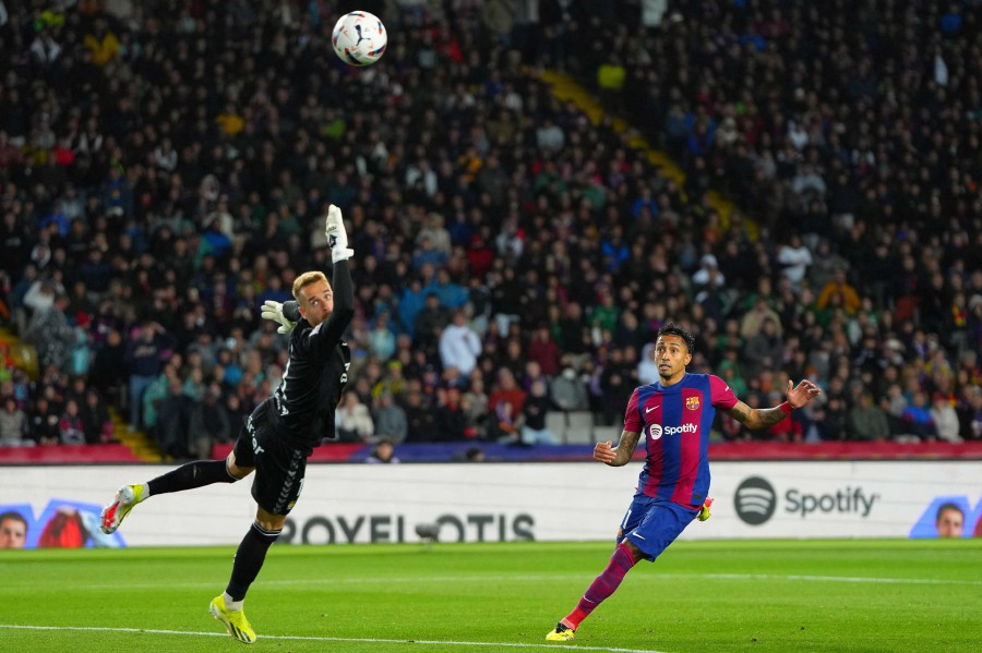 Barcelona's Brazilian forward #11 Raphinha scores past Las Palmas' Spanish goalkeeper #01 Aaron Escandell during the Spanish league football match between FC Barcelona and UD Las Palmas at the Estadi Olimpic Lluis Companys in Barcelona on March 30, 2024. AFP PIC