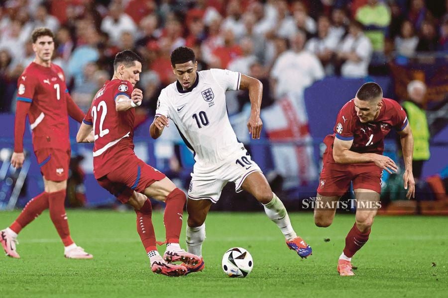 England's Jude Bellingham (centre) and Serbia's Sasa Lukic (left) vie for the ball during Sunday’s Euro 2024 Group C match at the Arena AufSchalke in Gelsenkirchen on Sunday. AFP PIC 