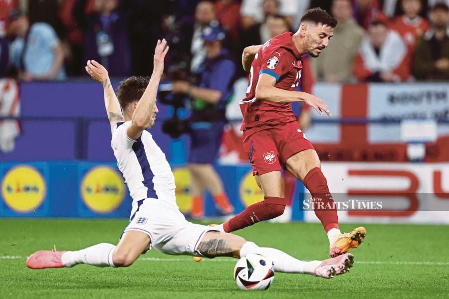 Serbia's Filip Mladenovic (in red) and England's John Stones vie during Sunday’s Euro 2024 Group C match at the Arena AufSchalke in Gelsenkirchen. AFP PIC 