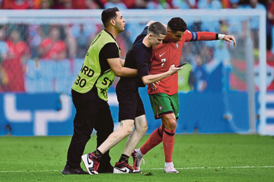 A pitch invader takes a selfie photograph with Portugal's forward Cristiano Ronaldo during the UEFA Euro 2024 Group F football match between Turkey and Portugal at the BVB Stadion in Dortmund. (Photo by INA FASSBENDER / AFP)