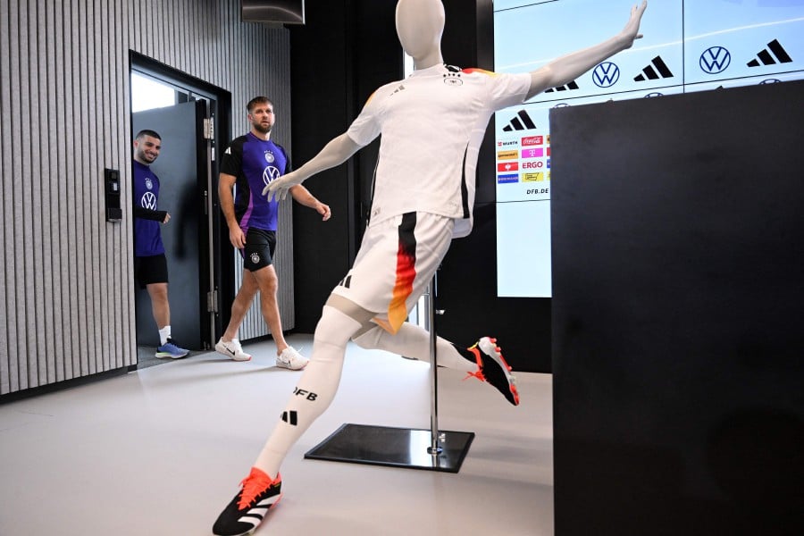 Germany's forward Deniz Undav (L) and Germany's forward Niclas Fuellkrug arrive for a press conference past a mannequin wearing the new German kit made by Adidas after a training session of the German national football team on March 21, 2024 in Frankfurt am Main, western Germany, in preparation of the team's international friendly football matches against France and the Netherlands. Germany's national football teams will wear jerseys made by US sportswear giant Nike from 2027, the German Football Association (DFB) said on March 21, 2024, ending a decades-long kit partnership with domestic outfitter Adidas. AFP PIC